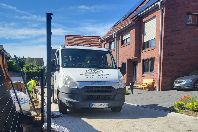 Hausmeisterservice Dahlmann Weißes Lieferfahrzeug steht auf einem gepflasterten Parkplatz vor einem Wohnhaus.